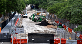 Construction on Speedway, showing traffic dividers in the foreground and construction equipment in the background